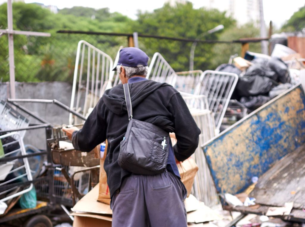 Image of the back of a waste picker collecting recyclables on a cart.