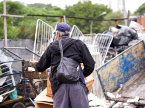 Image of the back of a waste picker collecting recyclables on a cart.
